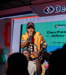 The host on the microphone in front of the DevFest After Party screen.