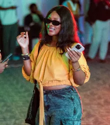 A guest in a yellow top and sunglasses, phone in hand.